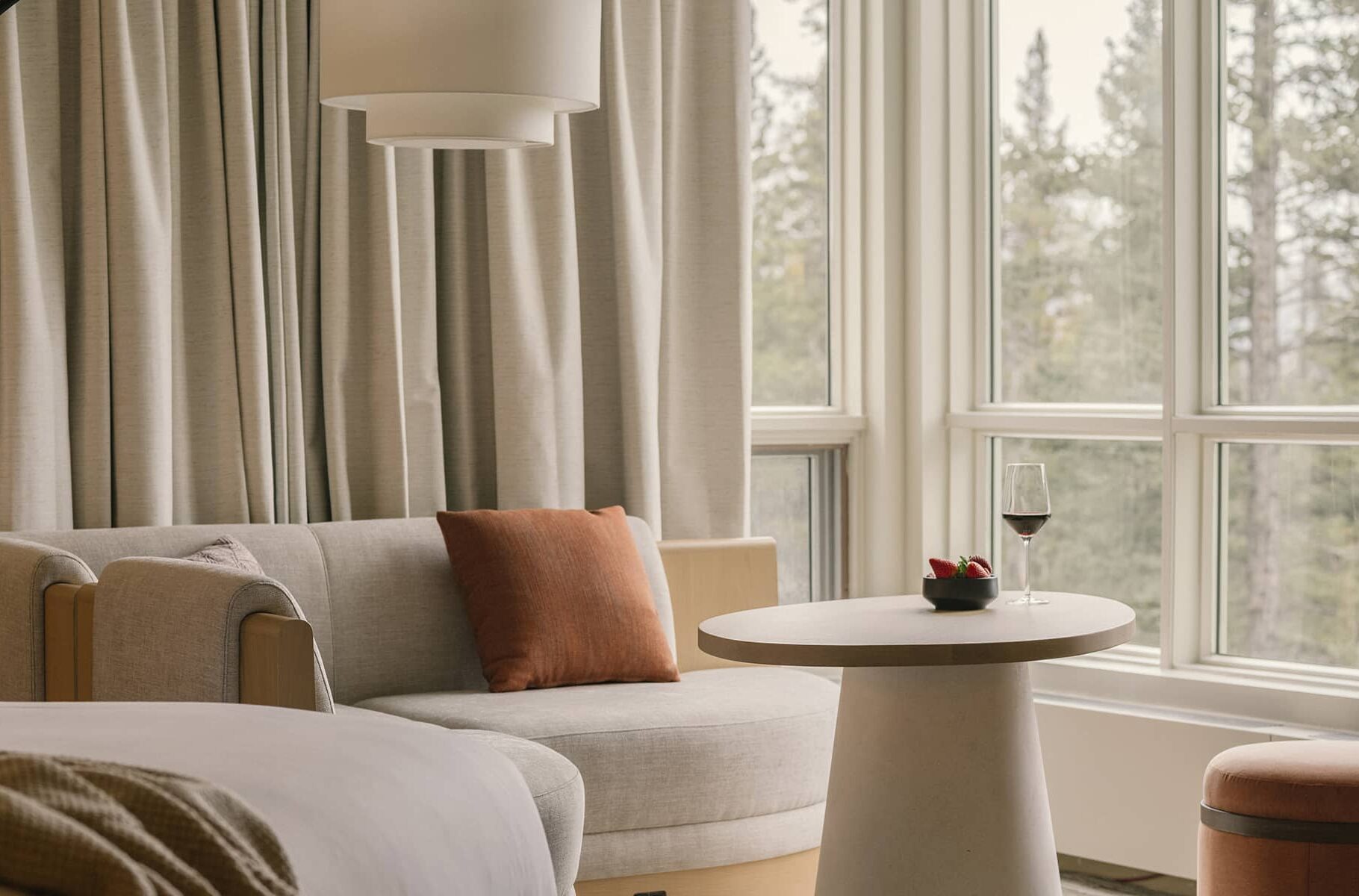A cozy window nook overlooking a serene forest, perfect for relaxing with a glass of wine