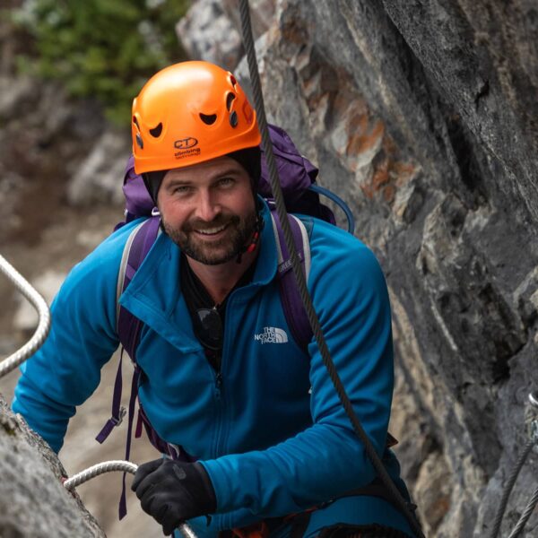 Harnessed climber pauses along Mount Norquay’s Via Ferrata, steady on iron rungs with rock walls rising around him.