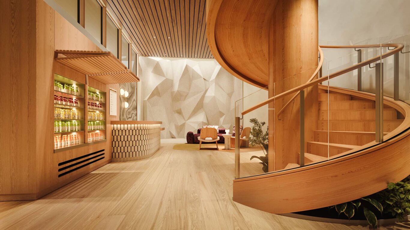 The wellness reception at Rimrock Banff, Emblems Collection features a curved wooden staircase, a juice bar with bottled drinks, seating area, and sculpted climbing wall.