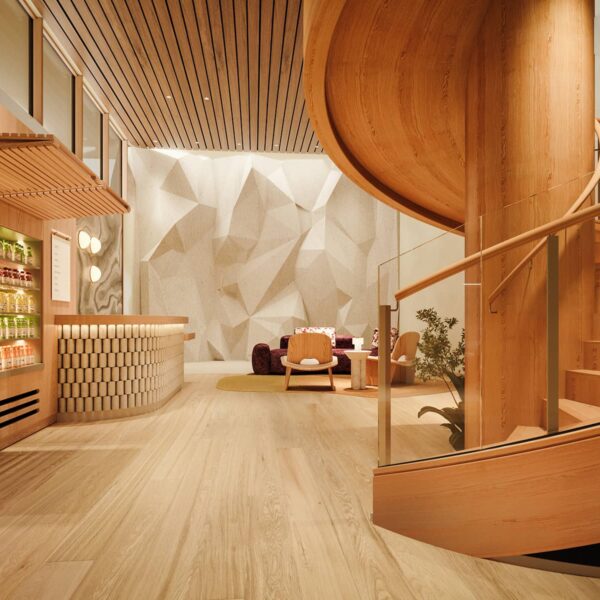 en::The wellness reception at Rimrock Banff, Emblems Collection features a curved wooden staircase, a juice bar with bottled drinks, seating area, and sculpted climbing wall.| fr::La réception de l’espace bien-être du Rimrock Banff, Emblems Collection, comprend un escalier incurvé en bois, un bar à jus, un coin salon et un mur d’escalade sculpté.| es::La recepción de bienestar en Rimrock Banff, Emblems Collection cuenta con una escalera curva de madera, un bar de jugos, un área de descanso y una pared esculpida para escalar.
