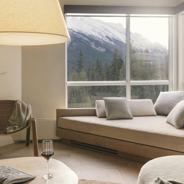 A bright living space in a Rimrock Banff one-bedroom suite featuring soft neutral furnishings, warm natural light, and mountain views framed by large windows.