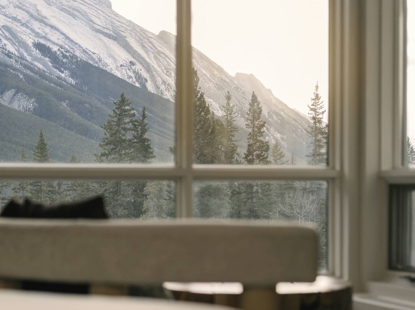 A serene mountain view from a Rimrock vista view room, showcasing rising peaks and evergreen trees bathed in soft natural light.