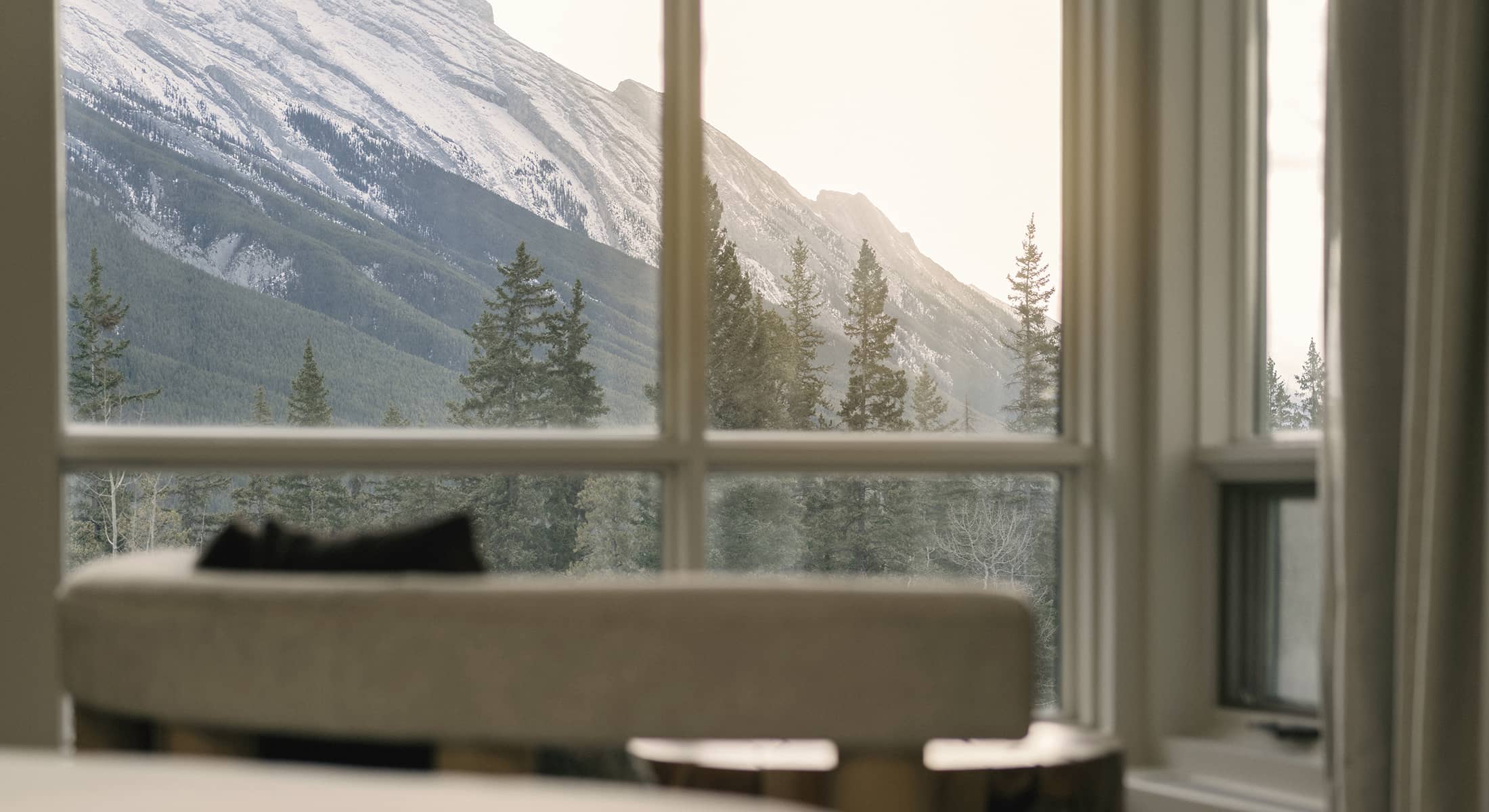 A serene mountain view from a Rimrock vista view room, showcasing rising peaks and evergreen trees bathed in soft natural light.