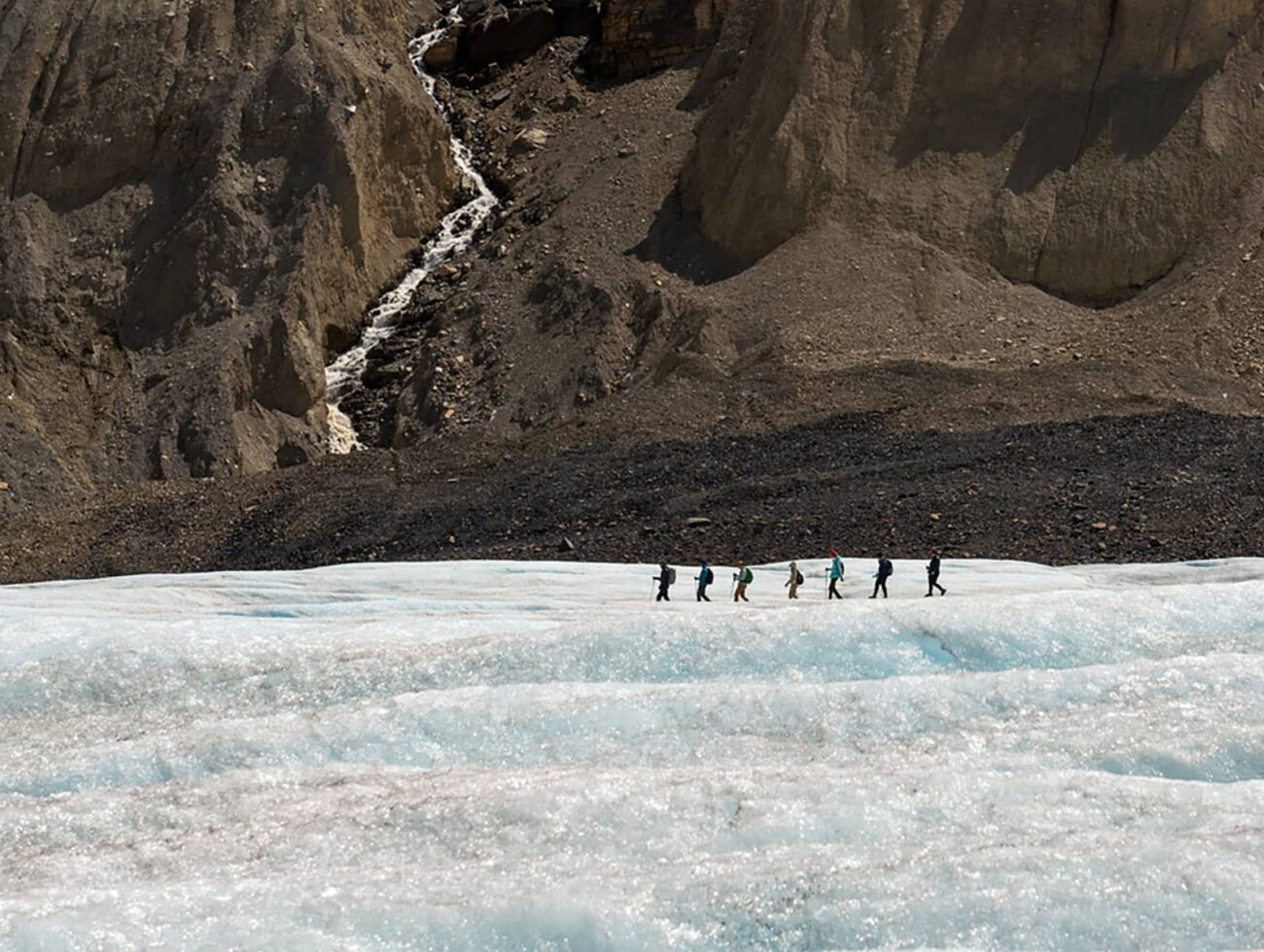 Expansive view across the Athabasca Glacier, highlighting textured ice fields framed by steep rock walls in the Canadian Rockies.