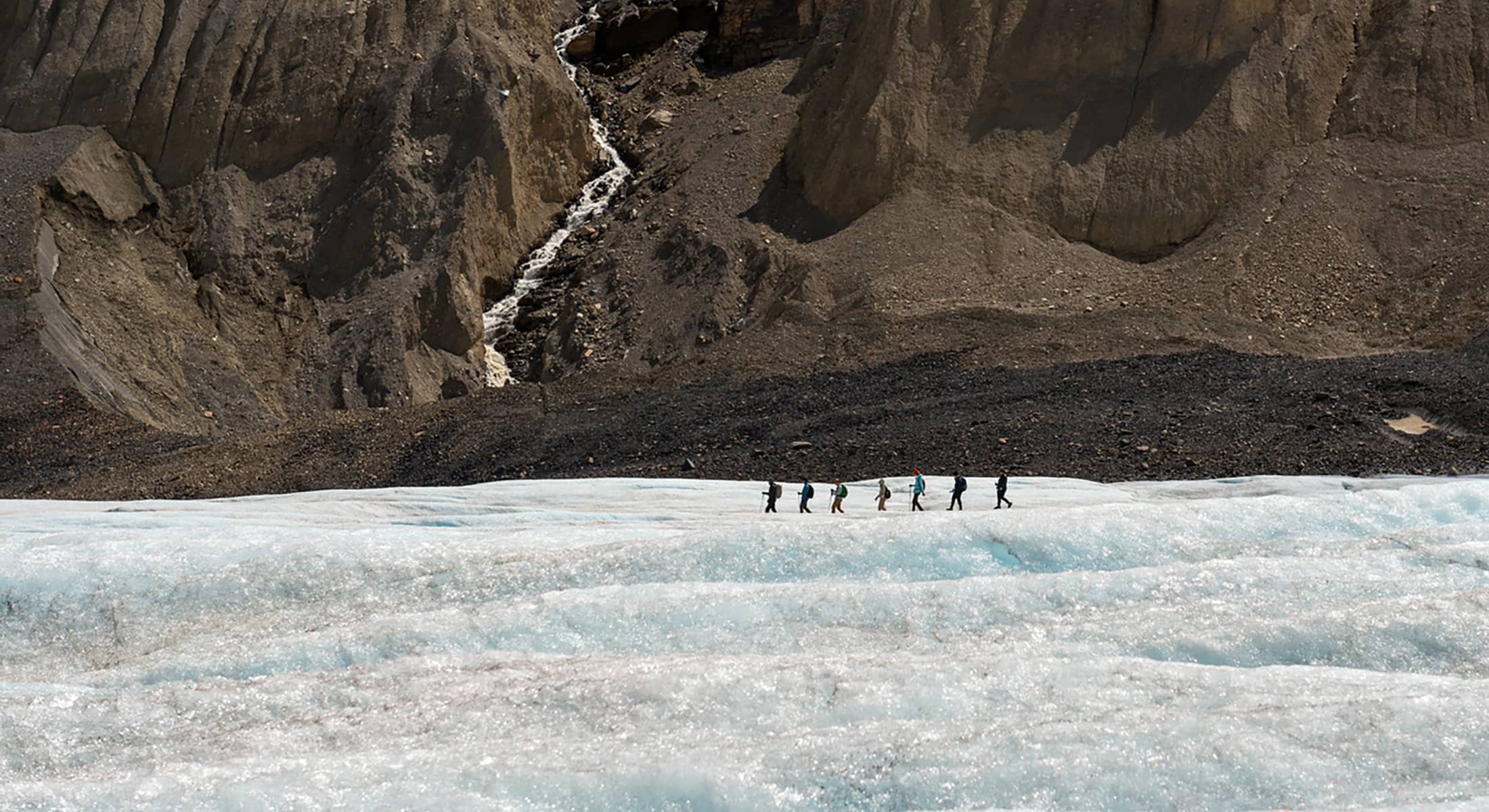 Expansive view across the Athabasca Glacier, highlighting textured ice fields framed by steep rock walls in the Canadian Rockies.