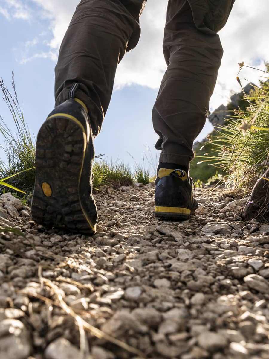 Hiker walking on mountain path, hiking boots detail.