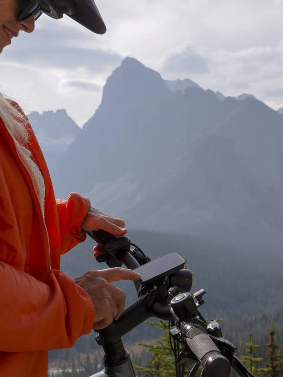 woman touches digital screen on e-bicycle in mountains, Banff National Park, Canadian Rockies