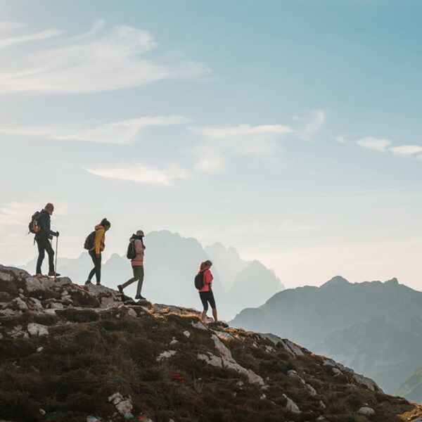 en::Small group hiking along a rocky alpine ridge in Banff National Park with layered mountain silhouettes in the distance. | fr::Petit groupe évoluant sur une crête alpine rocheuse dans le parc national Banff, avec des silhouettes de montagnes en dégradé à l’horizon. | es::Un pequeño grupo camina a lo largo de una cresta alpina rocosa en el Parque Nacional de Banff, con siluetas de montañas superpuestas a lo lejos.