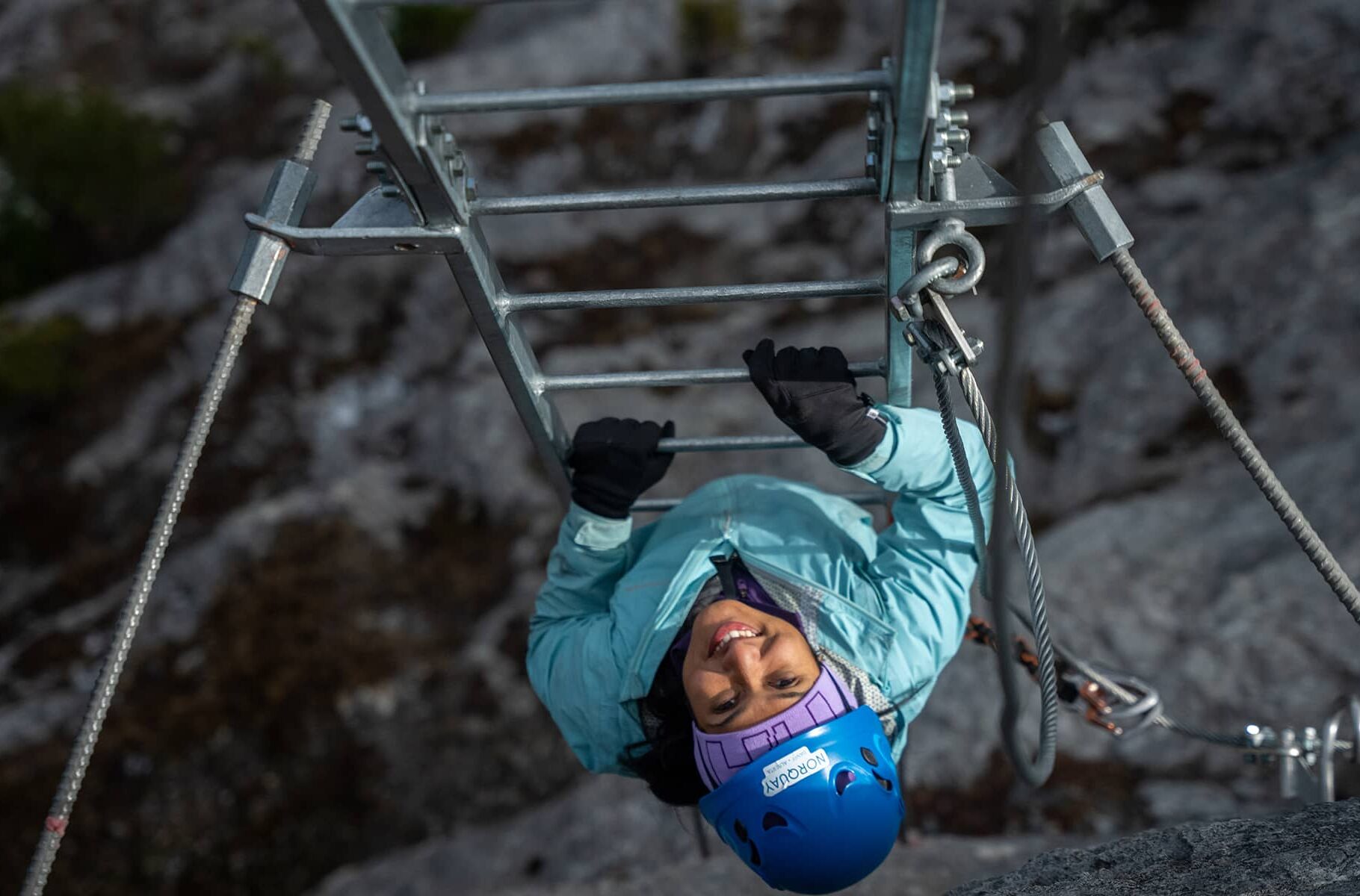 Guest ascending a Via Ferrata ladder on Mount Norquay, harnessed and guided, moving confidently along the rock face.