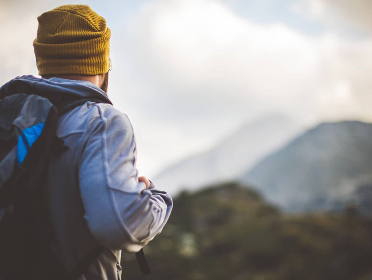 Traveler in Banff National Park with backpack looks on a mountain peak in front of him.