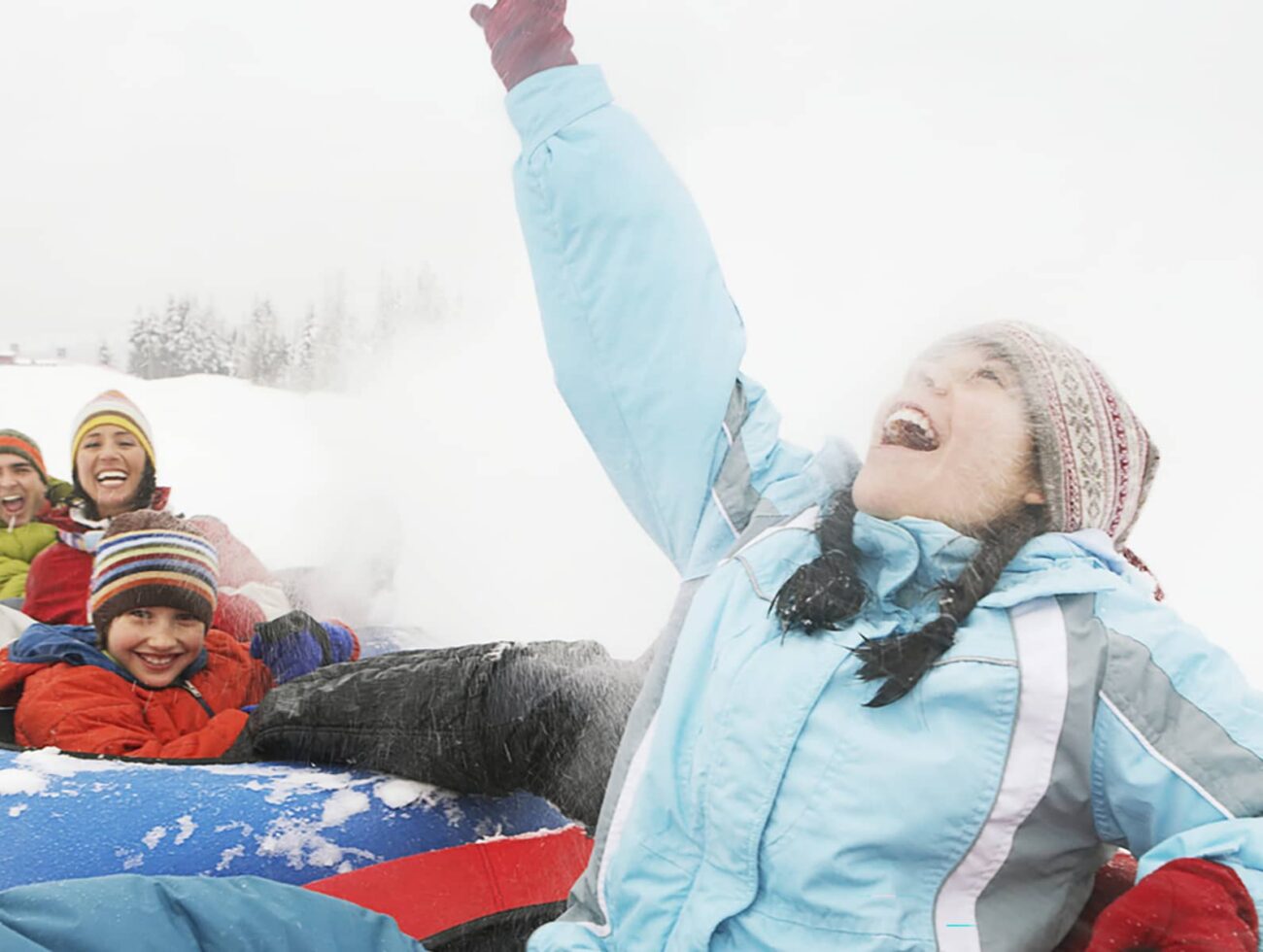 A group of adults and children snow tubing together at Mount Norquay on a winter day.