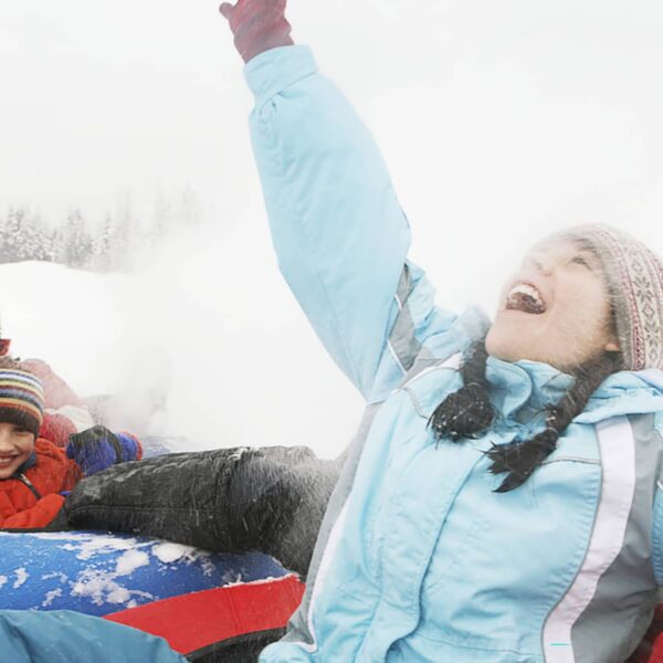A group of adults and children snow tubing together at Mount Norquay on a winter day.