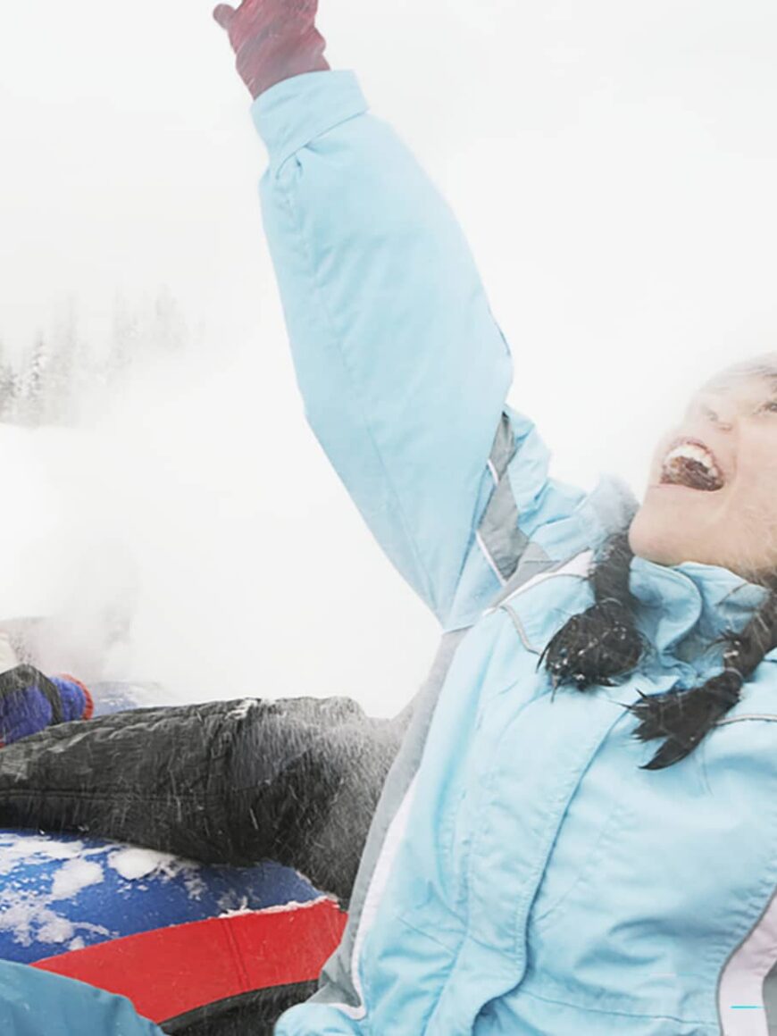 A group of adults and children snow tubing together at Mount Norquay on a winter day.