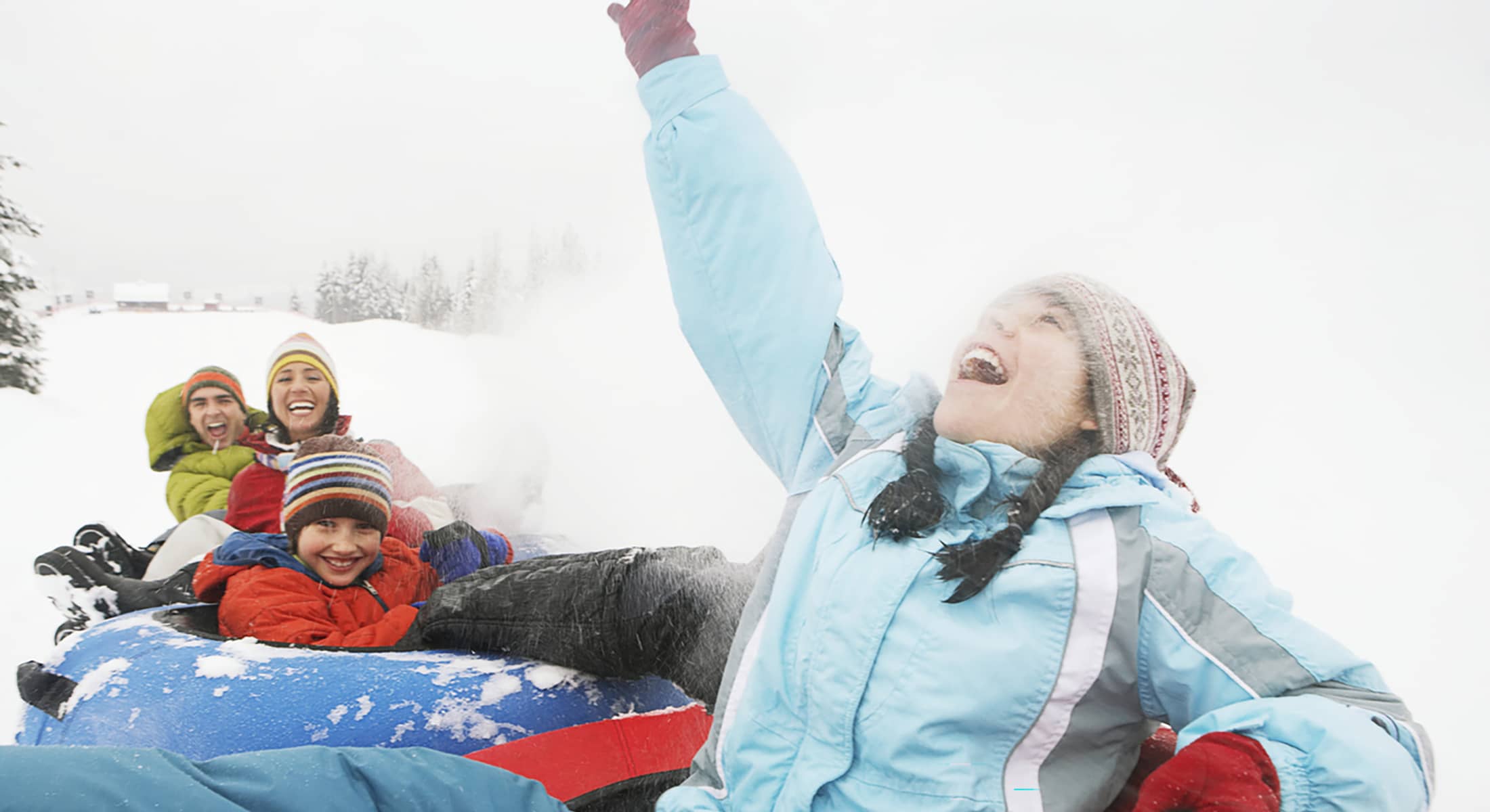 A group of adults and children snow tubing together at Mount Norquay on a winter day.