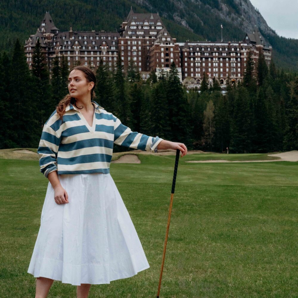 woman standing on the golf course at the Banff Springs Golf Course with the Banff Springs Hotel in the background