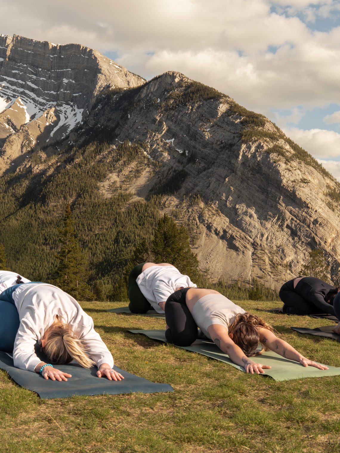 Guests participate in an outdoor yoga session during wellness classes in Banff, surrounded by the dramatic peaks of the Canadian Rockies.