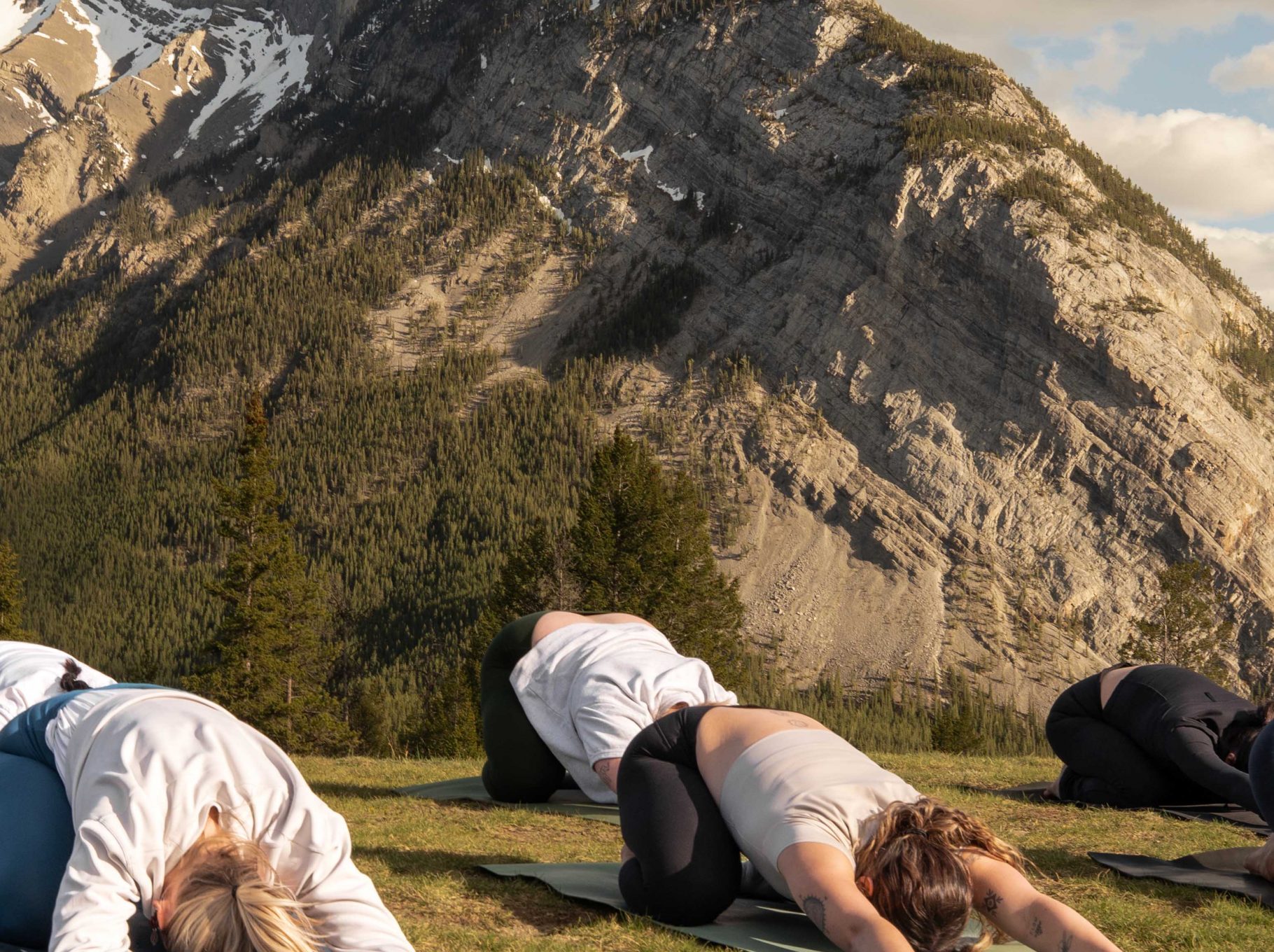 Guests participate in an outdoor yoga session during wellness classes in Banff, surrounded by the dramatic peaks of the Canadian Rockies.