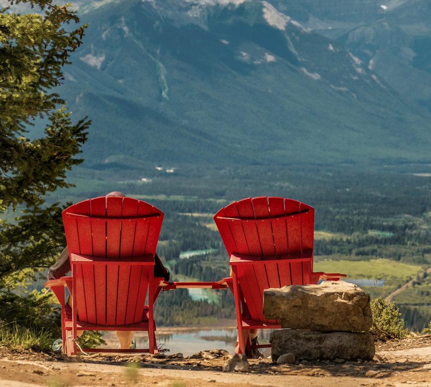 Two people relax in red chairs overlooking Tunnel Mountain in Banff