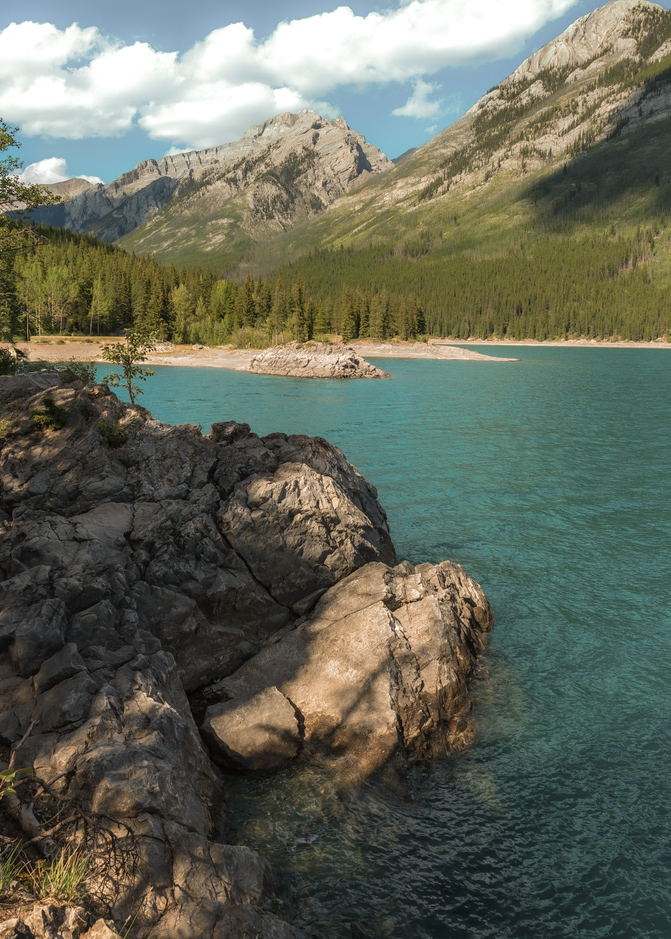 Turquoise waters of lake minnewanka reflecting the cloudy sky and surrounding mountains in banff national park, a breathtaking natural wonder in the canadian rockies