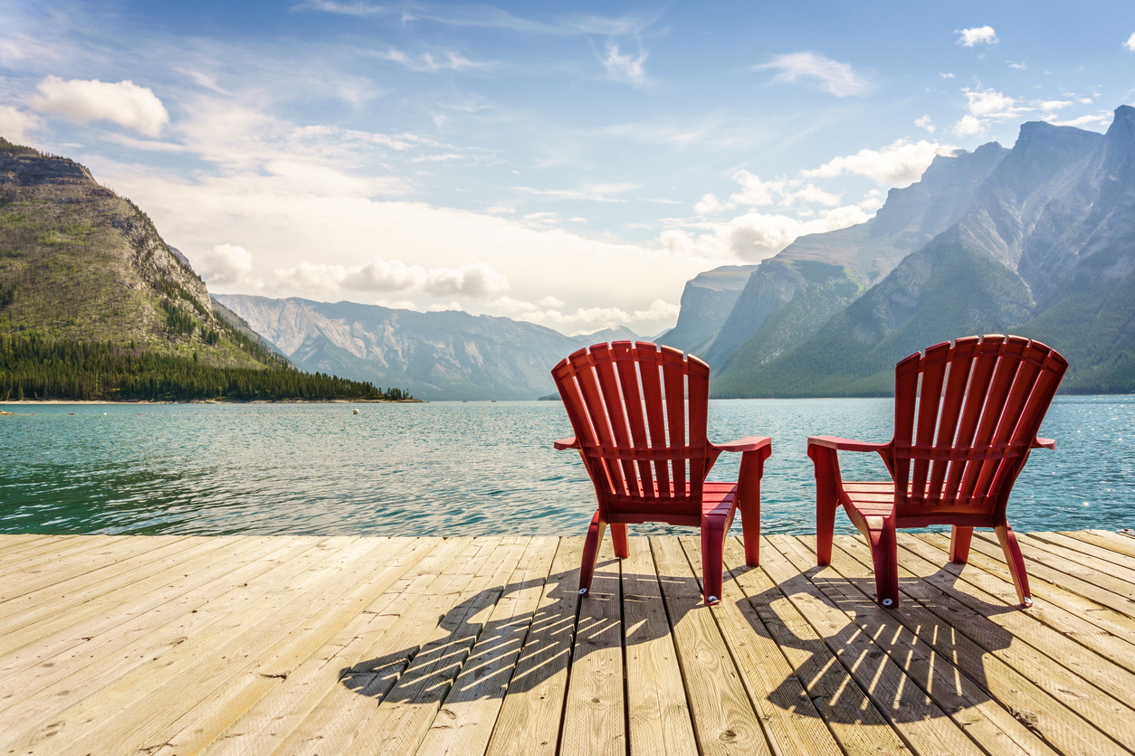 Red chairs on the deck at Lake Minnewanka overlooking the water on a sunny summer dat
