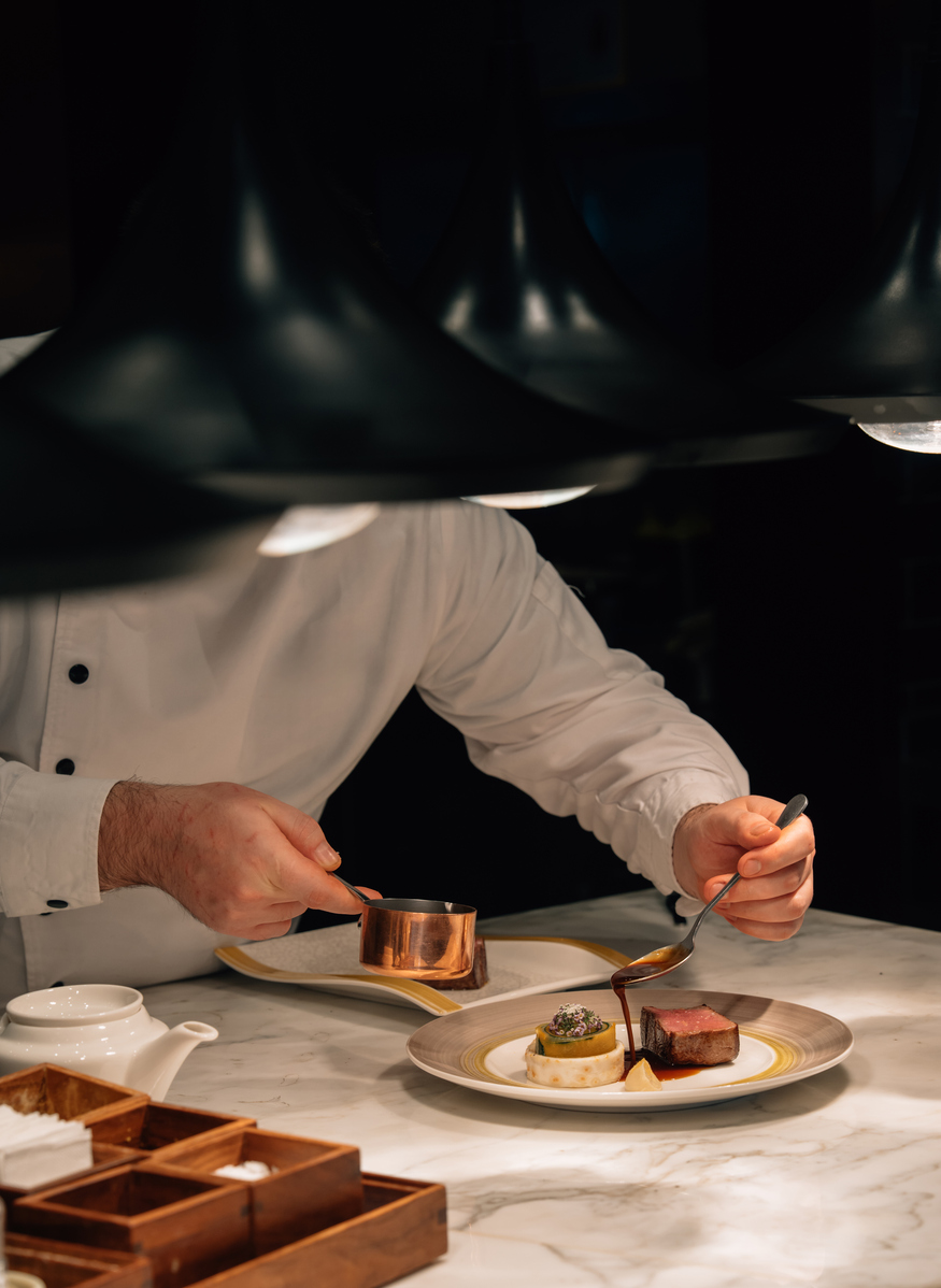 Chef decorating a plate while working in the kitchen at Parker's Table at Rimrock Banff,