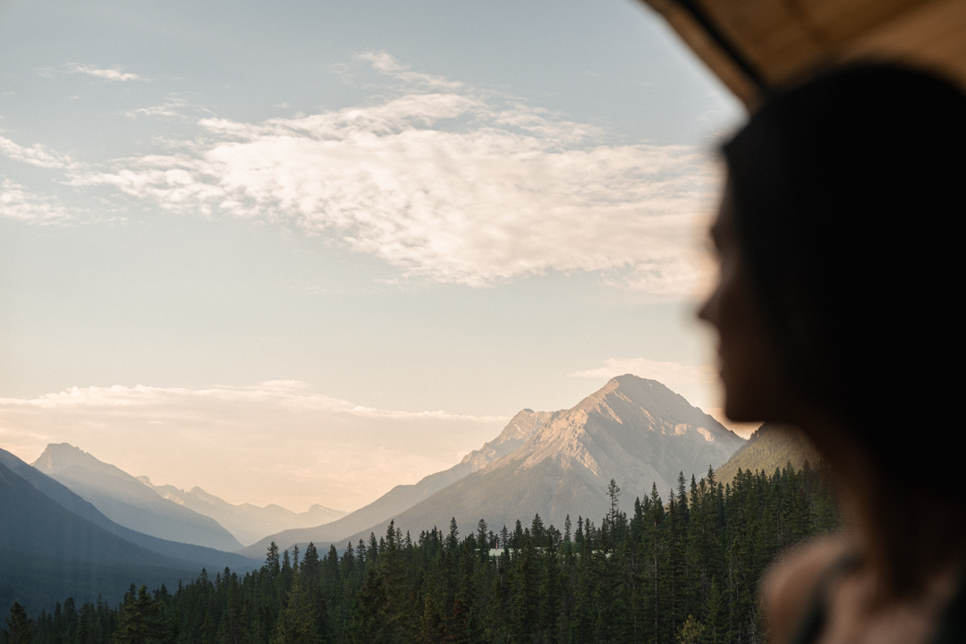 A woman inside of the sauna at Rimrock Banff overlooking the Spray Valley.